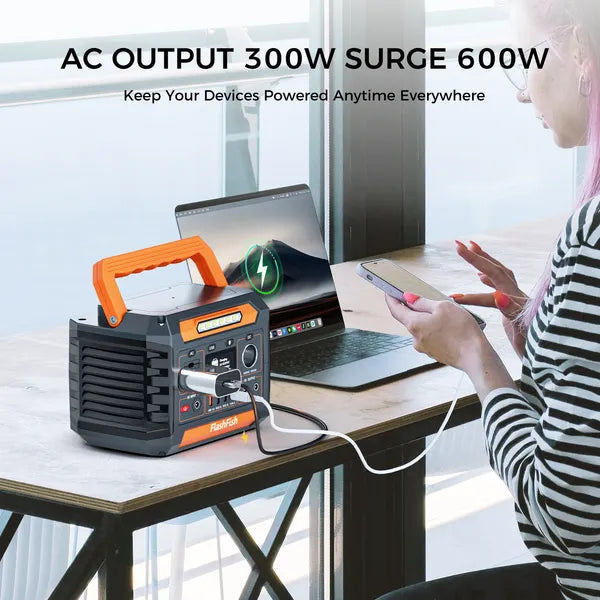Portable power station with AC output 300W surge 600W, used to power a laptop and phone on a desk.
