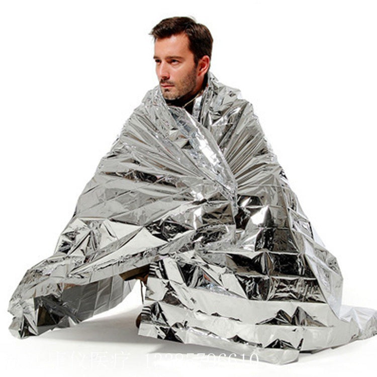 Person wrapped in a silver mylar blanket on a white background