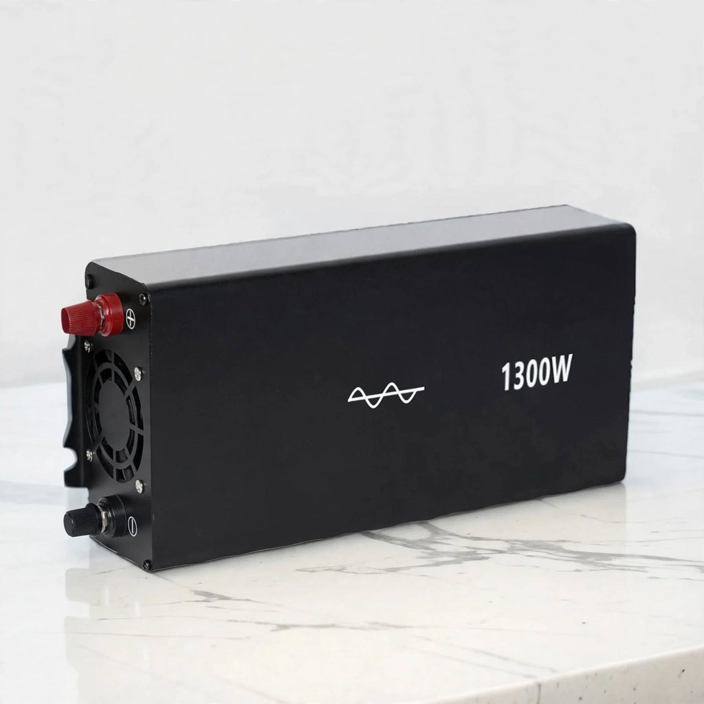 A black rectangular battery or power unit with a cooling fan on one end, a red terminal cap, and white printed text reading 1300W, photographed on a light marble-like surface against a pale background.