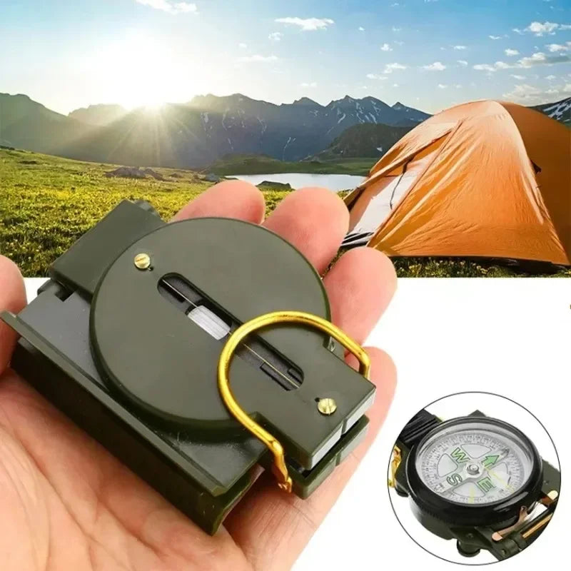 Hand holding a compass with a scenic camping background