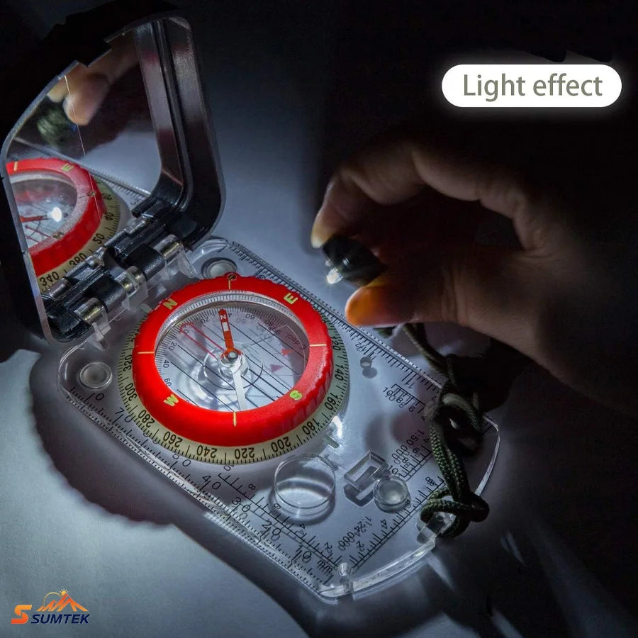 A clear plastic and metal compass with a red compass housing and measurement markings, shown open with a hand holding a small light source to demonstrate illumination. The image includes a 'Light effect' label and a SUMTEK logo in the corner.