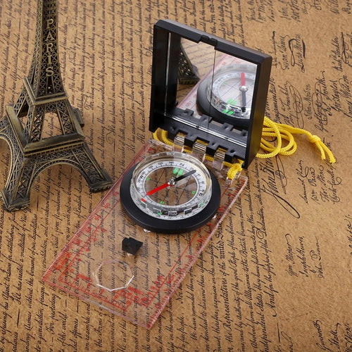 Compass with a clear cover on a textured surface resembling old paper with writing