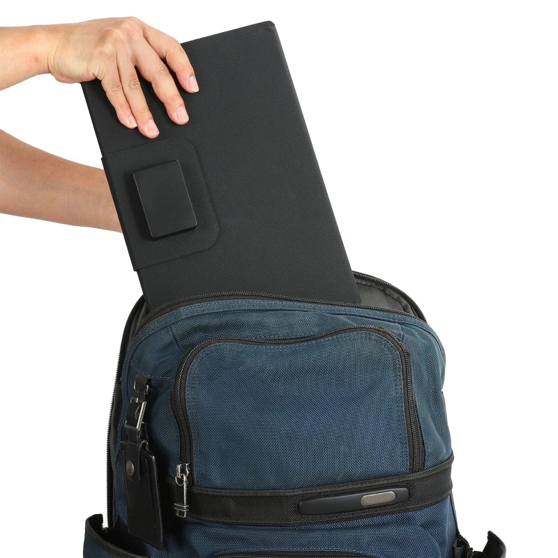 A hand inserting a black tablet into the main compartment of a blue nylon backpack, shown against a plain white background.