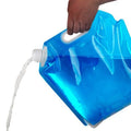 A translucent blue collapsible water bottle being held by a hand, with water pouring from the spout, on a white background.