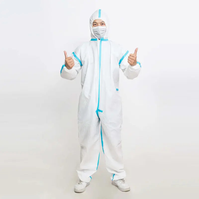A person wearing a white full-body protective suit with bright blue trim and a matching face mask, standing against a plain light background and giving two thumbs up.